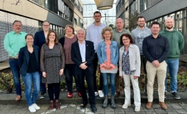 13 Personen stehen zusammen für ein Gruppenbild